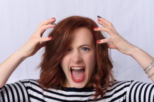 frustrated red head woman with red nail polish